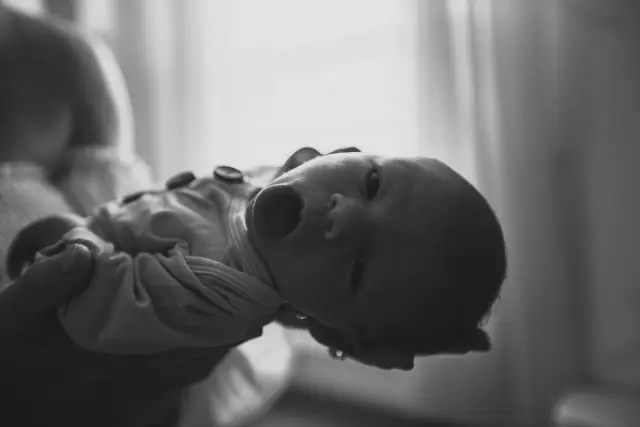 Black and white photo of a newborn stretching on the bed