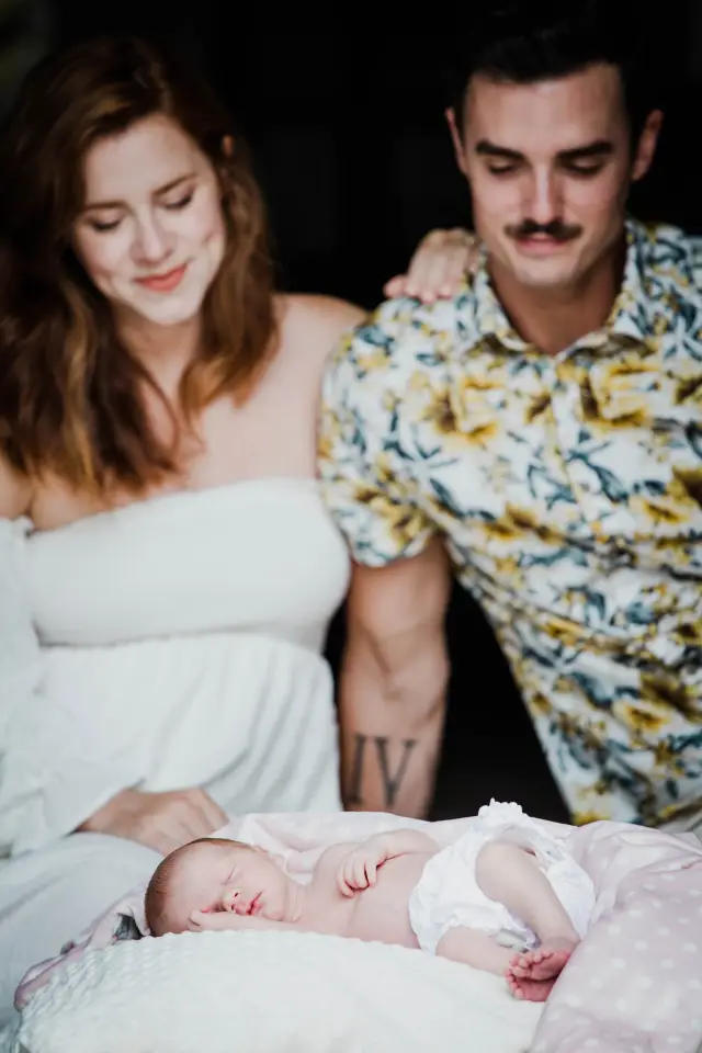 New parents smiling down at their newborn asleep on a pillow