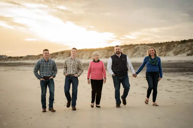 Family of five walking toward the camera on the beach at sunset