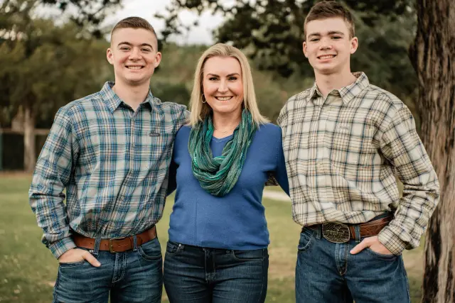 Mom with her two teenage sons in plaid shirts under the trees