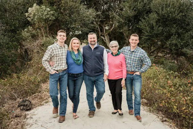 Family of five walking together down a sandy path through the trees