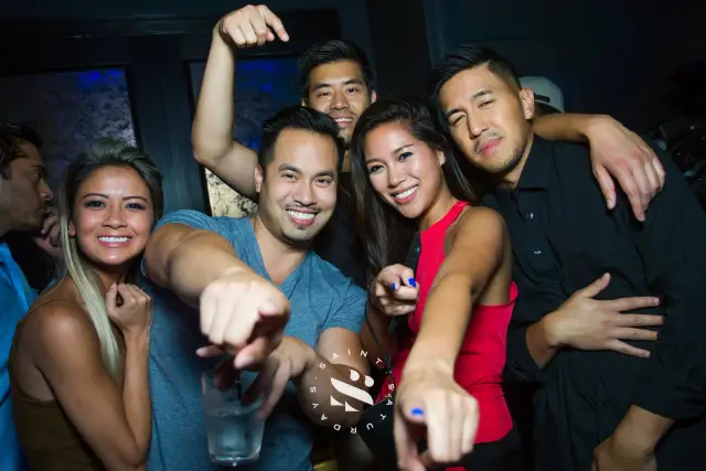Friends pointing at the camera and laughing at a nightclub