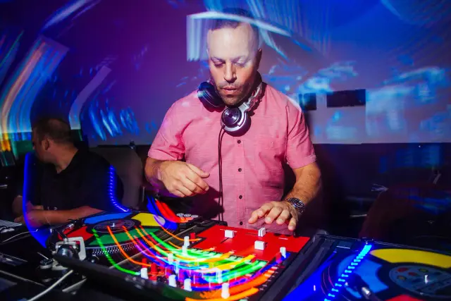 DJ in headphones spinning under colorful lights