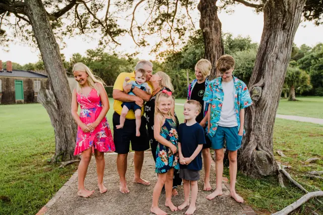 Kids and grandparents in matching tropical prints laughing under the live oaks