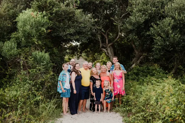 Extended family gathered on a sandy path between the trees