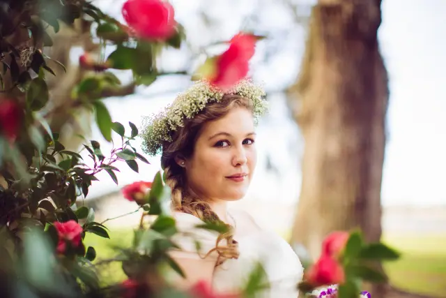 Bride with a baby's breath flower crown framed by pink camellia blossoms