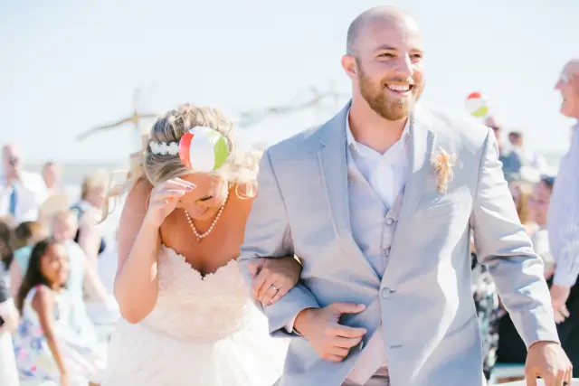 Bride and groom walking back up the aisle laughing as guests throw petals