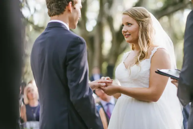 Bride and groom exchanging rings under the oaks during their outdoor ceremony