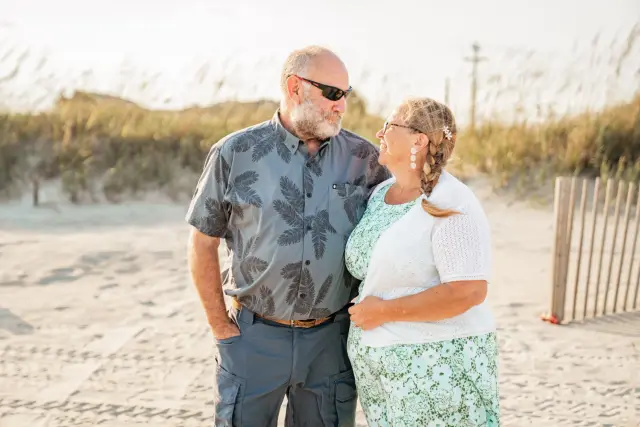 Smiling couple standing together on the beach by the dunes before a wedding